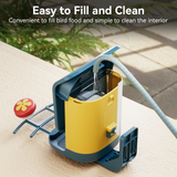 A bright yellow detachable bird seed bin from Nafnti being washed with a water hose for easy cleaning.
